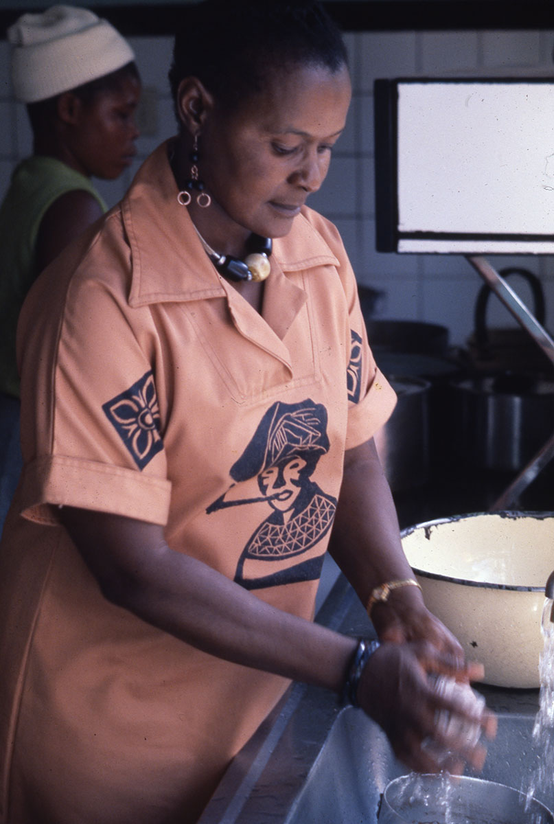 Color image of woman in orange tunic washing something in sink